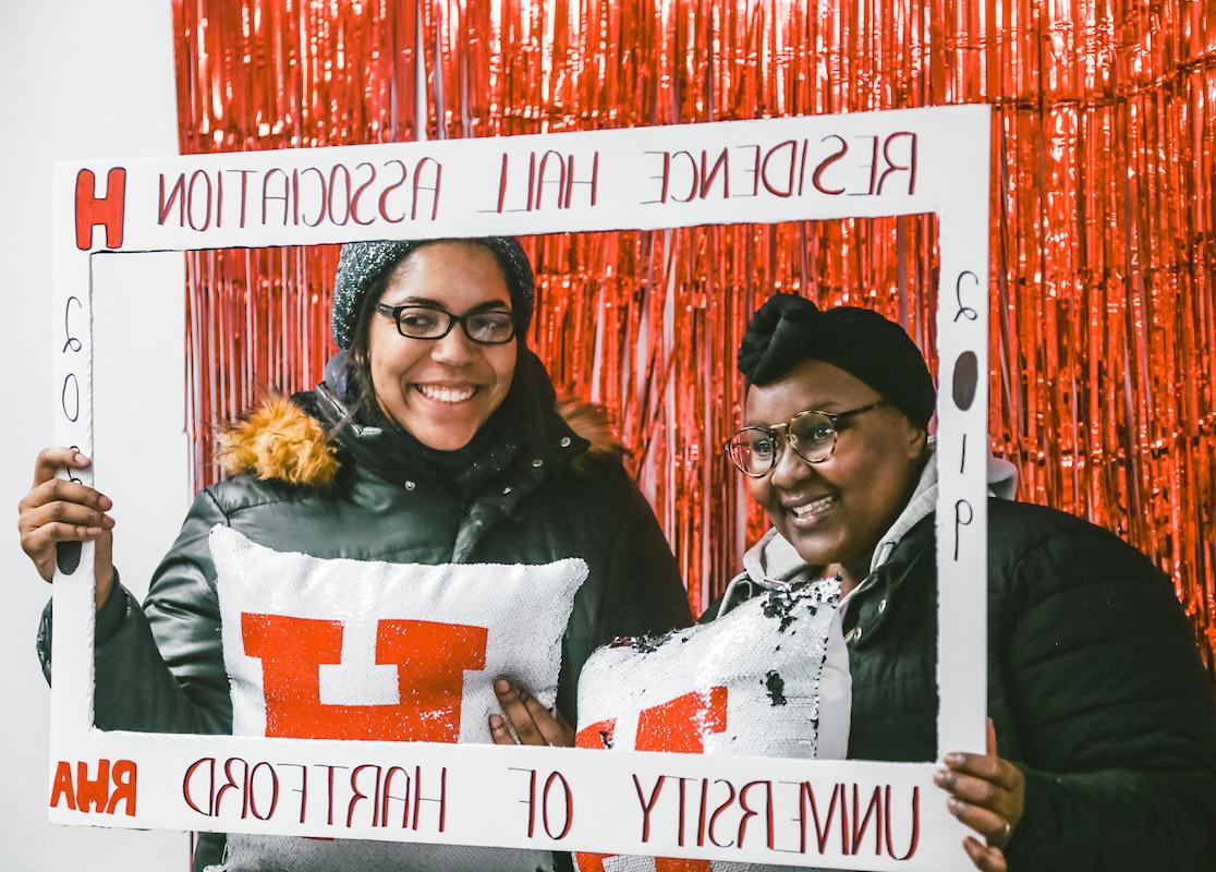 Image is of two students holding up a sign that says residence hall association